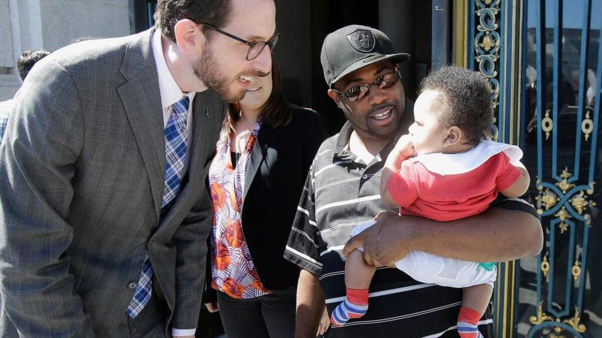 Alphonzo Jackson and his 6-month-old son, Isaiah, chat with San Francisco Supervisor Scott Wiener. The city this month became the nation’s first to require fully paid family leave.