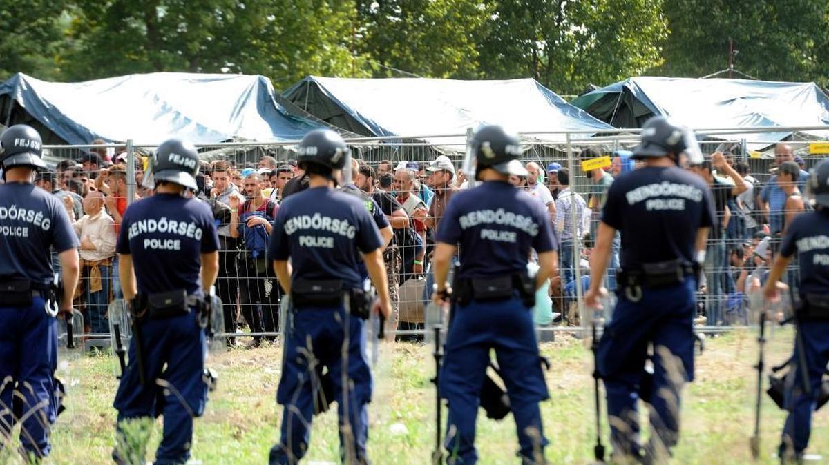 
Hungarian police guard migrants at a camp near Budapest on Friday after about 300 people broke out of the reception center near Hungary’s border with Serbia. 

