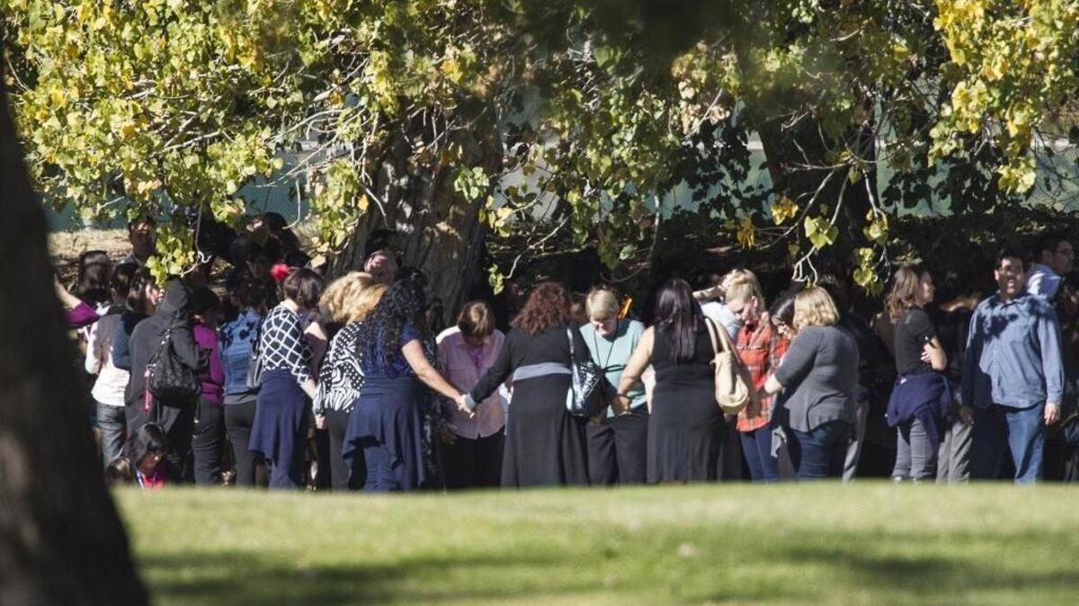 Evacuated workers pray on the San Bernardino Golf Course across the street from a mass shooting at the Inland Regional Center in San Bernardino on Wednesday.