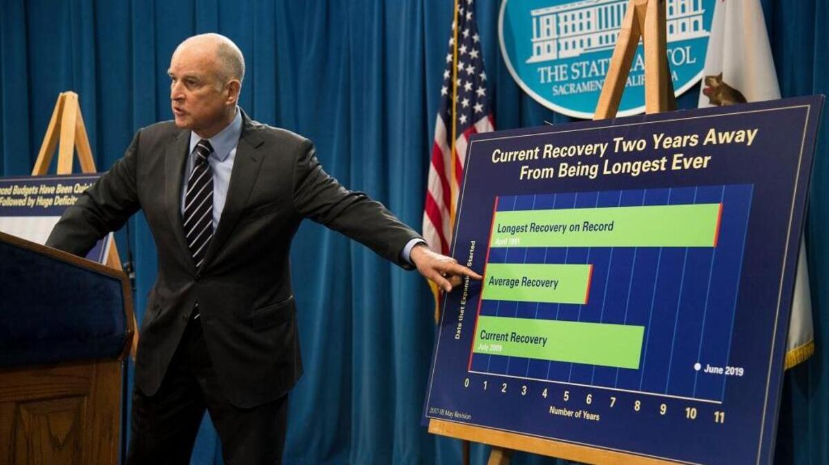 Gov. Jerry Brown refers to a chart regarding his revised budget plan, noting that an economic downturn is coming, during a news conference at the Capitol on Thursday in Sacramento.