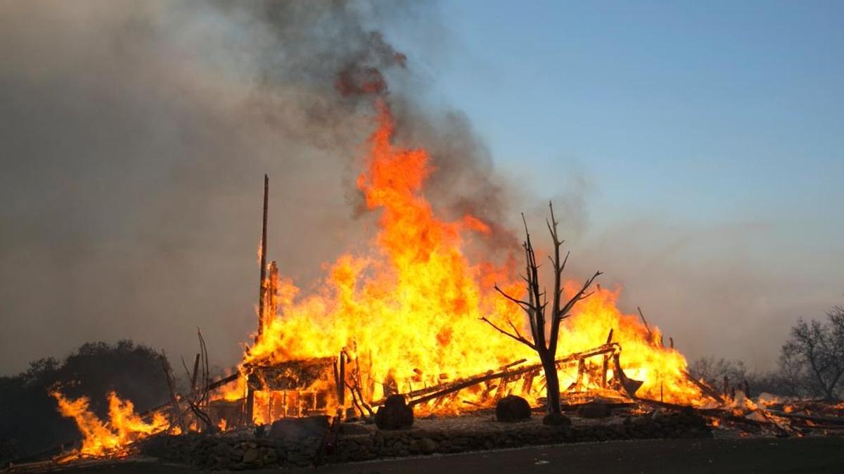 Flames from a wildfire consume a home Monday east of Napa.