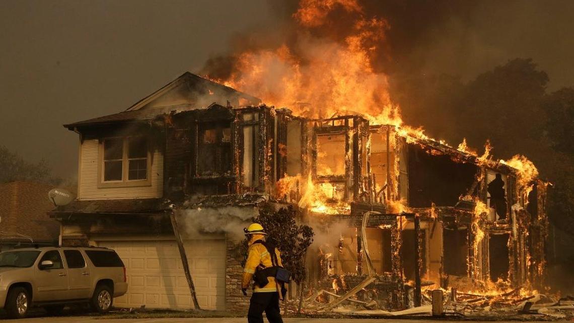 A firefighter walks near a burning house in Santa Rosa in October 2017. PG&E reported a $984 million loss because of wildfire losses.
