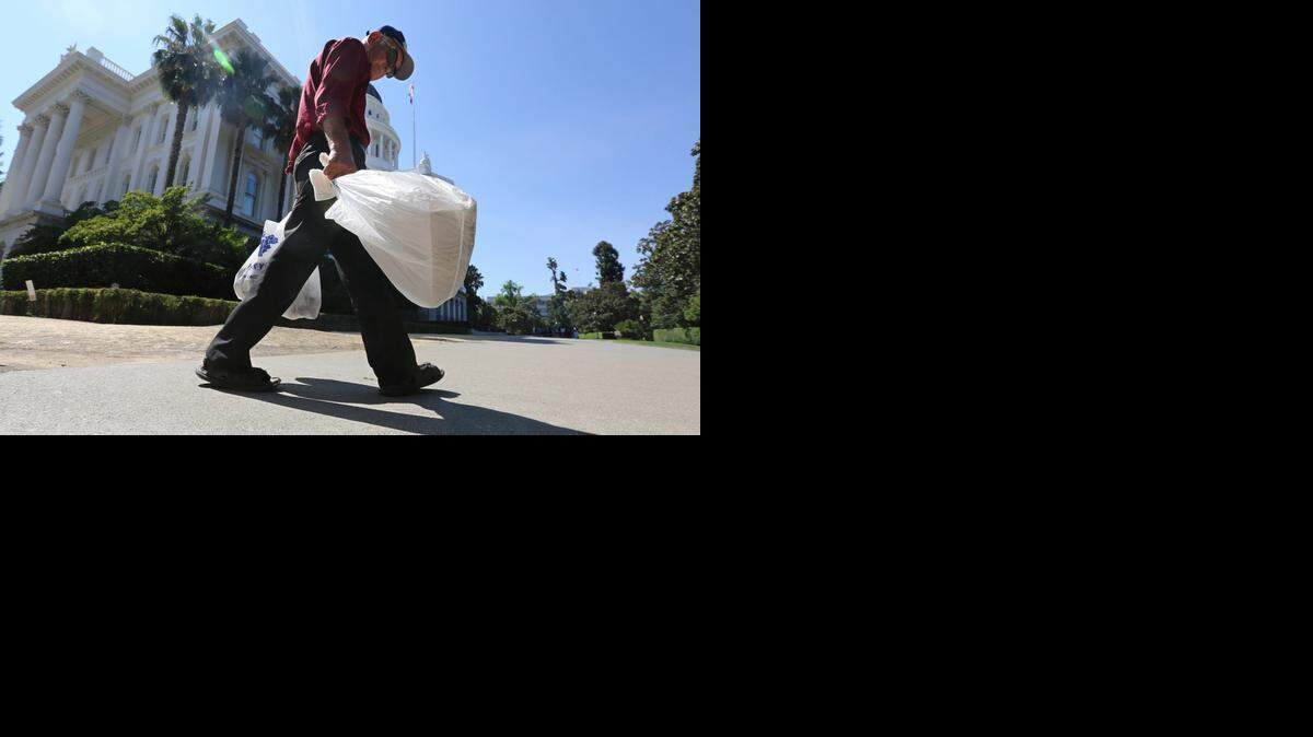 
A man carries single-use plastic bags past the state Capitol last August. The Sacramento City Council is to vote on a ban on Tuesday night.
