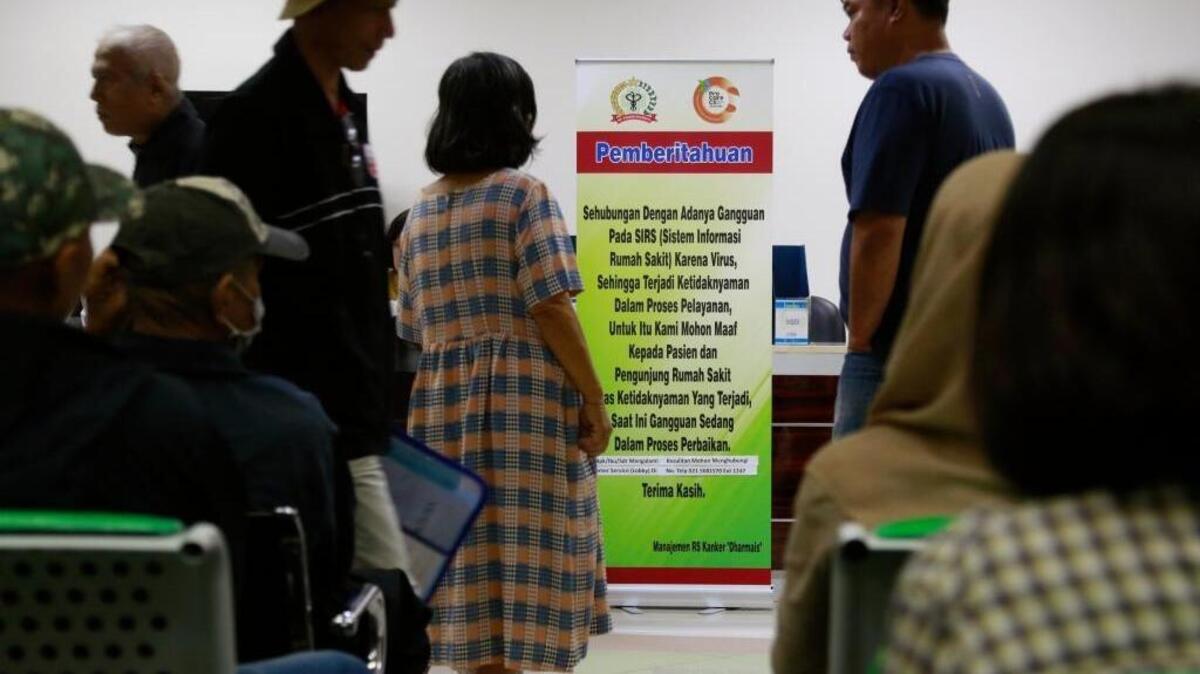 Patients wait near a sign informing about delays caused by a global ransomware attack that struck Dharmais Cancer Hospital in Jakarta, Indonesia on Monday.