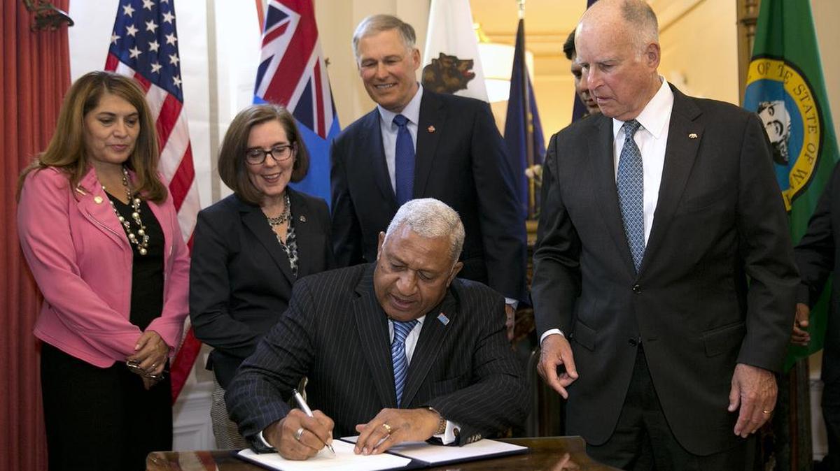 Gov. Jerry Brown, right, watches as Frank Bainimarama, the prime minister of Fiji, signs a climate change accord on Tuesday at the Governor’s Mansion. Looking on are, from left, Assemblywoman Sharon Quirk-Silva, D-Fullerton, Oregon Gov. Kate Brown and Washington State Gov. Jay Inslee.