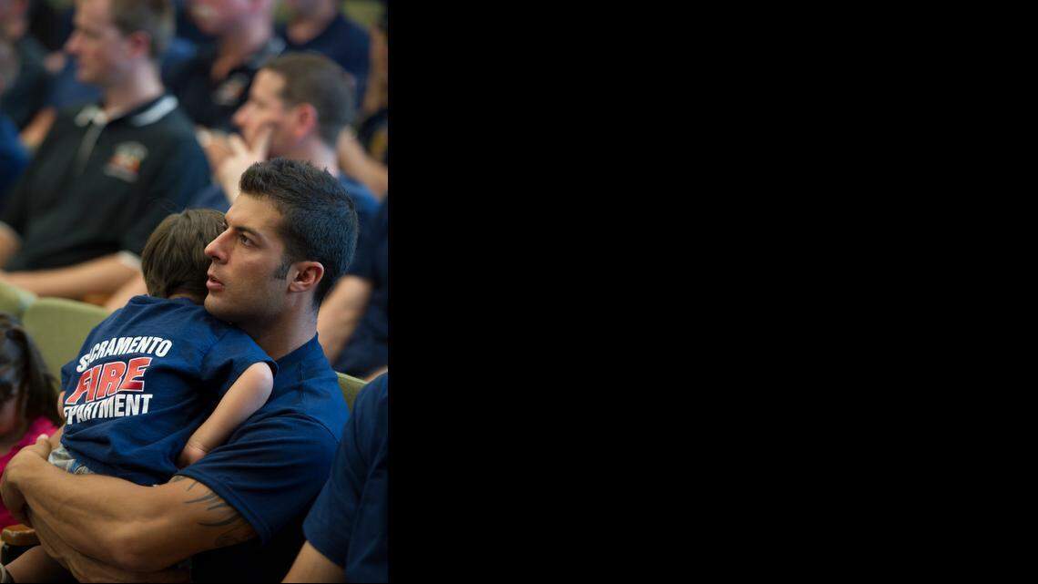 
Sacramento firefighter Masoud Baruk holds his son Cayd during City Council budget hearings in 2012. Council members are starting to debate health care benefits to city retirees, including firefighters.
