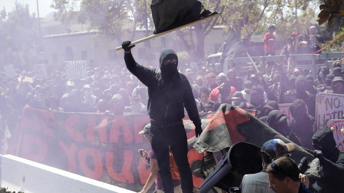 An anti-fascist demonstrator jumps over a barricade during a free speech rally Sunday, Aug. 27, 2017, in Berkeley, Calif.