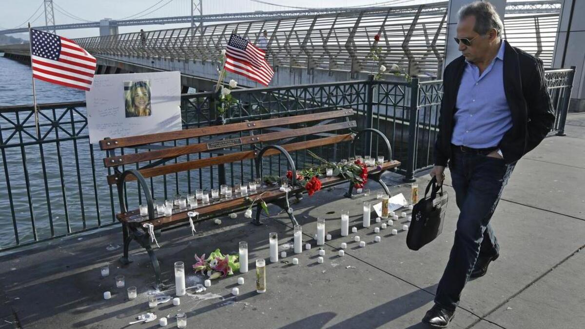 A man walks past candles, flowers, and a photo of Kate Steinle at a memorial site on Pier 14 in San Francisco on Friday. In this fiercely liberal city, city leaders remained attached to San Francisco's sanctuary city status despite a not guilty verdict in a killing that sparked feverish immigration debates because the man who fired the gun was in the country illegally after being deported five times.