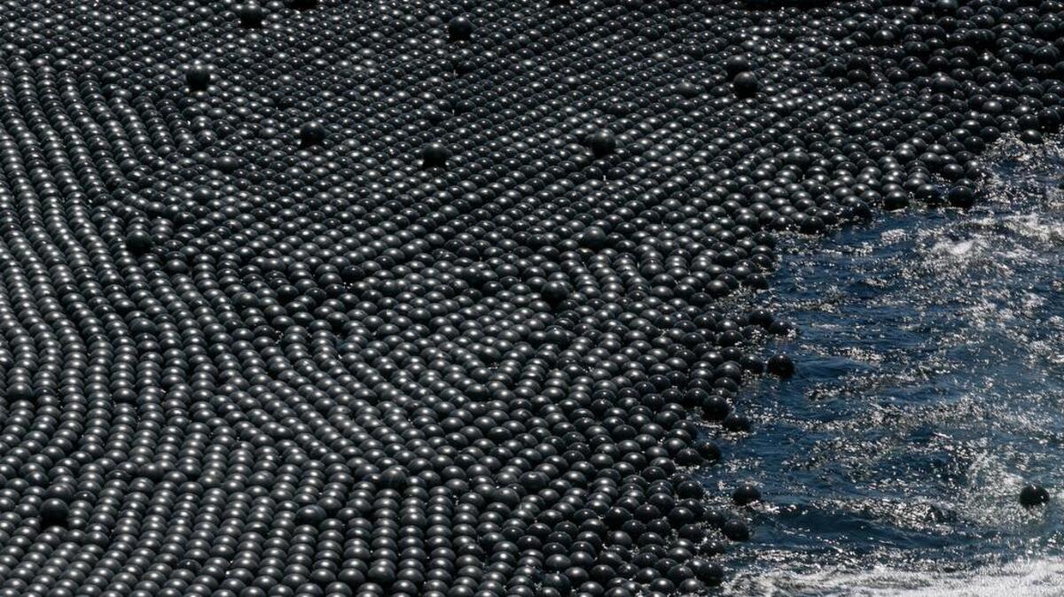 
The Los Angeles Reservoir is covered with 96 million black plastic balls Wednesday. The city has completed a program of covering its open-air reservoirs with floating, 4-inch diameter “shade balls” to protect water quality by blocking sunlight from penetrating the 175-acre surface of the reservoir, preventing chemical reactions that can cause algae blooms and other problems.
