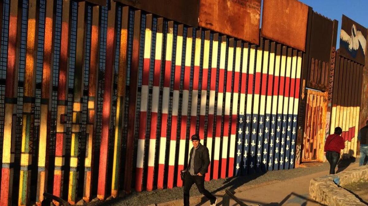 People pass graffiti along the border structure in Tijuana, Mexico. President Donald Trump is seeking funds for a wall along the entire border and has threatened to cut federal grants for immigrant-protecting “sanctuary cities.”