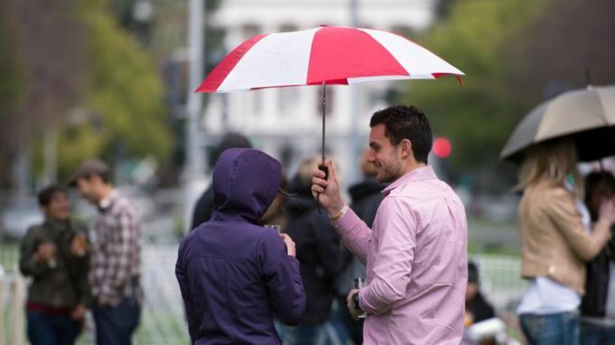 A couple holds an umbrella to keep dry in a light rain during the annual Capitol Beer Fest at the Capitol Mall.