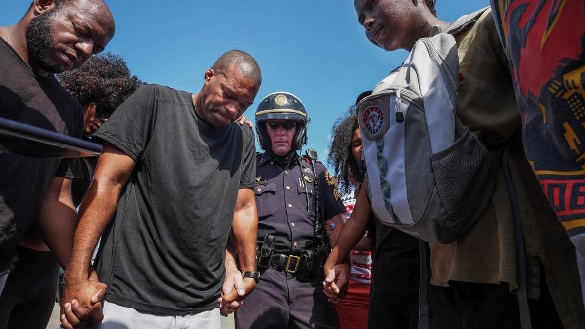 Dallas Police Sgt. Paul Hinton prays with a group of Black Lives Matter marchers in Dallas on Sunday, July 10, 2016.