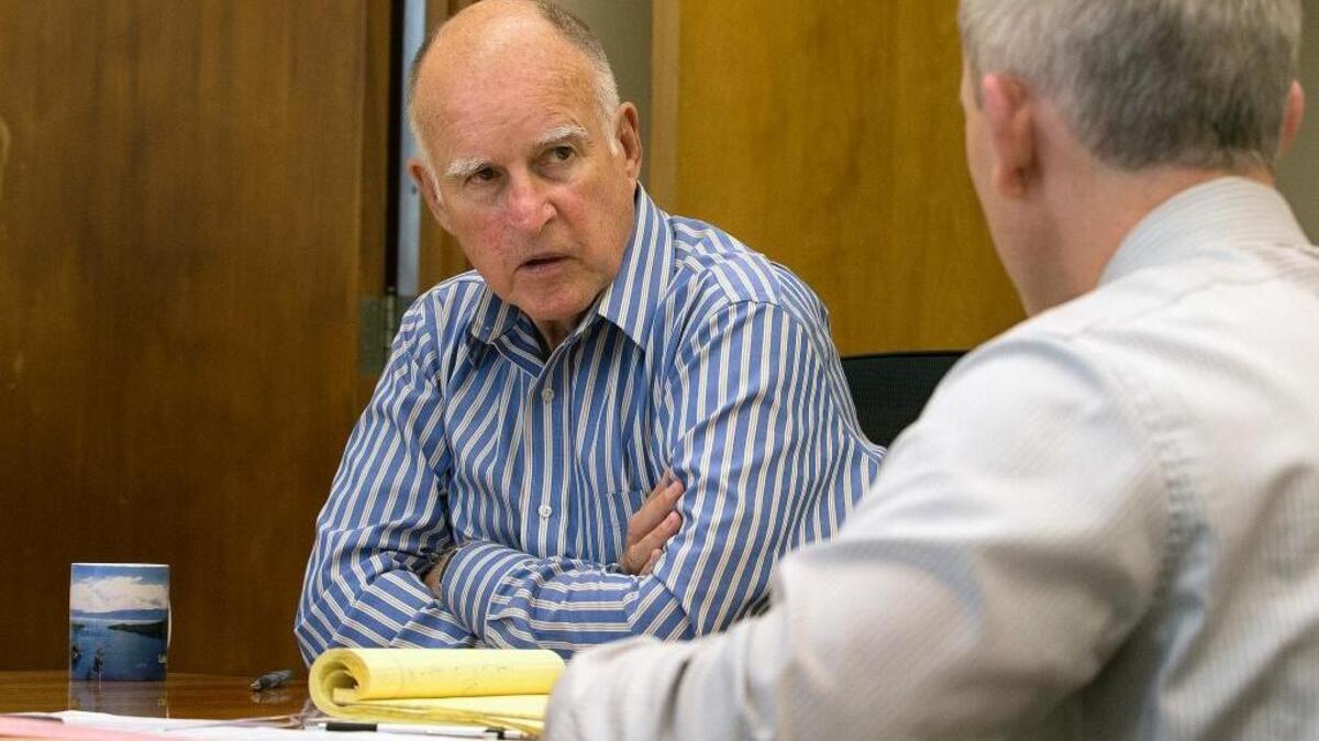 Gov. Jerry Brown discusses a bill under consideration for his signature with Tom Dyer, his chief deputy legislative affairs secretary. Last week, Brown signed legislation expanding California’s decades-old ban on assault weapons and regulating ammunition sales.