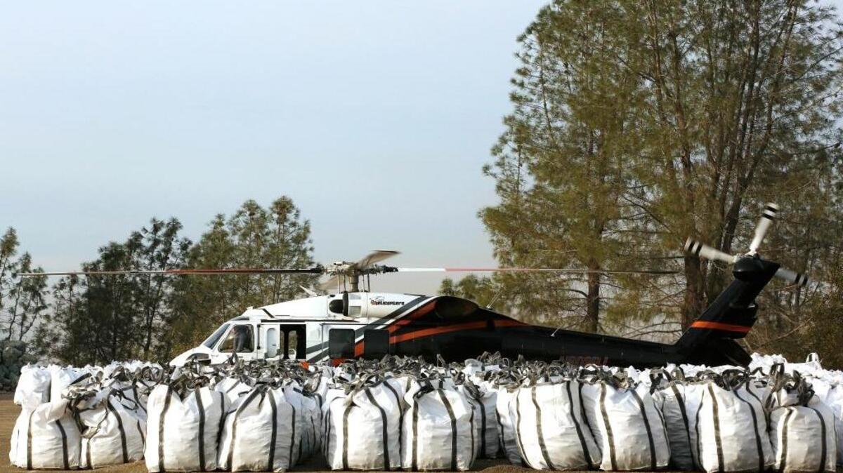 A helicopter sits at a staging area behind bags of rocks near the Oroville Dam on Monday. Officials from the California Department of Water Resources were considering using helicopters to drop loads of rock on the eroded spillway at Lake Oroville, Calif.