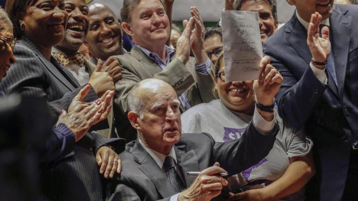 Gov. Jerry Brown shows the bill he signed to enact the highest statewide minimum wage, $15 an hour, by 2022.