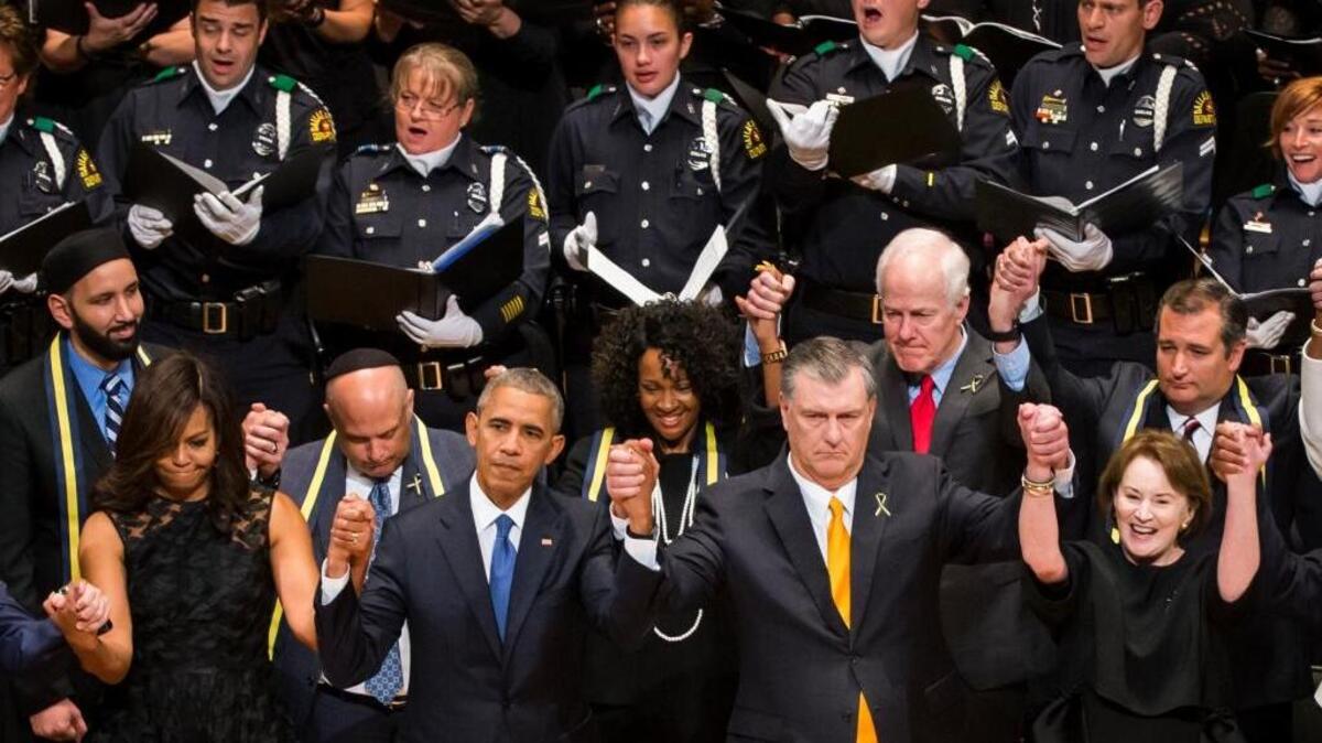 President Barack Obama raises hands with Dallas Mayor Mike Rawlings along with Michelle Obama and Micki Rawlings during an interfaith memorial service in Dallas on Tuesday for five law enforcement officers killed in an ambush at a Black Lives Matter rally.
