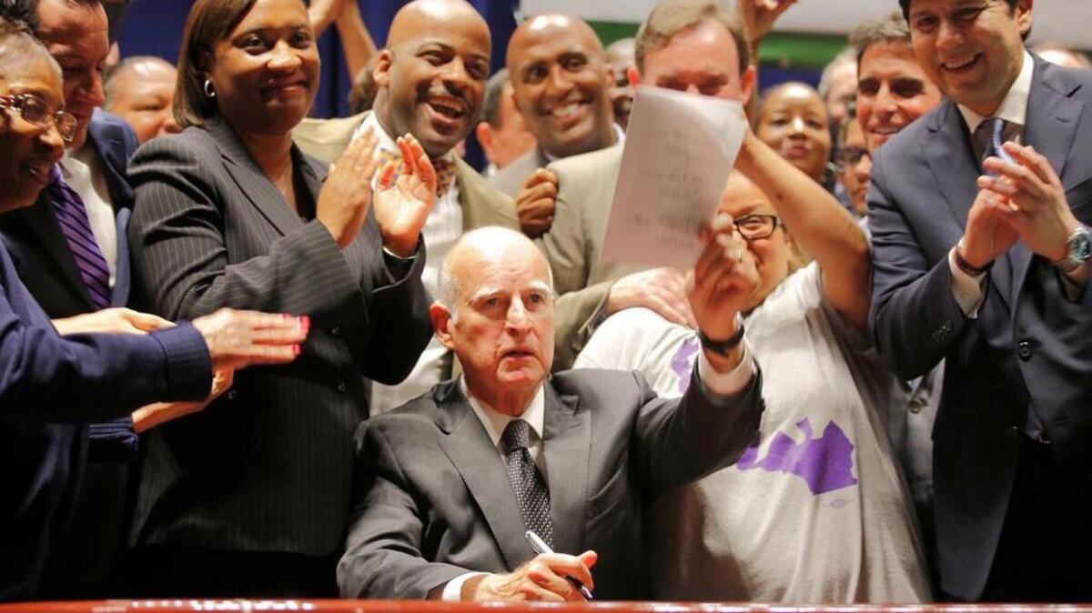 Gov. Jerry Brown signs a minimum wage bill at the Ronald Reagan State Building on April 4.