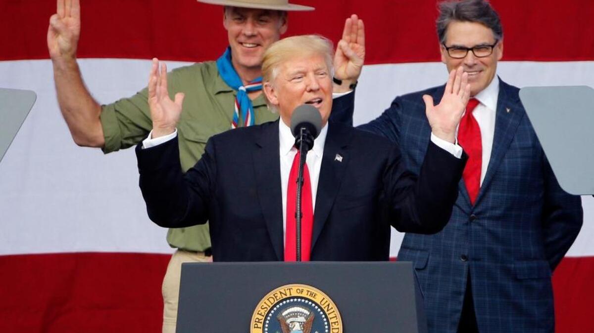 President Donald Trump gestures as former boys scouts, Interior Secretary Ryan Zinke, left, Energy Secretary Rick Perry, watch at the 2017 National Boy Scout Jamboree at the Summit in Glen Jean, W. Va., on July 24, 2017.