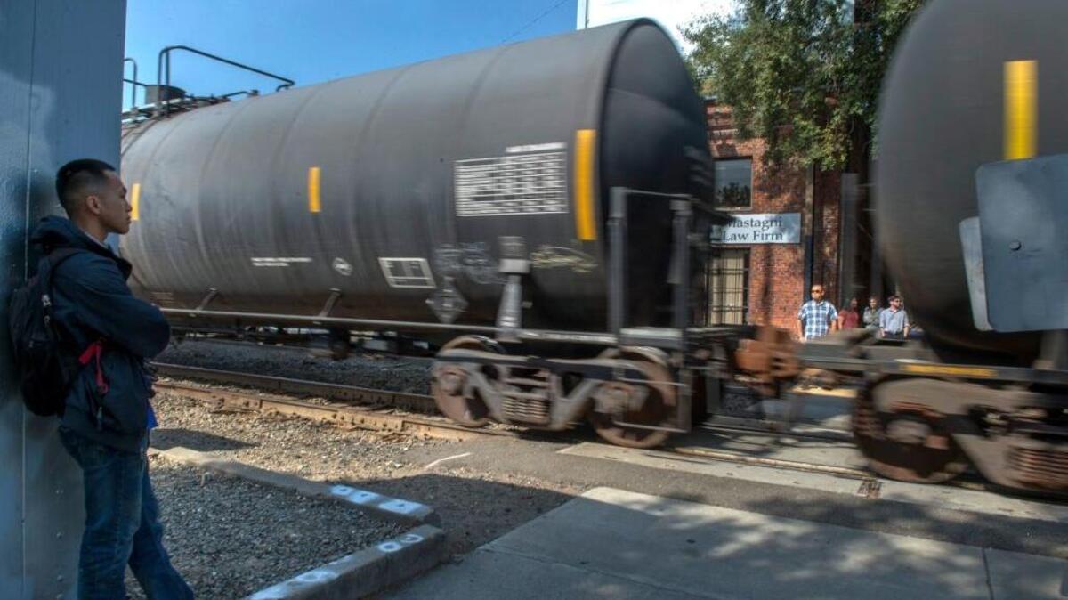 Kiemchai Saechao waits to cross the tracks at I Street after a train had been stalled in midtown on Tuesday.