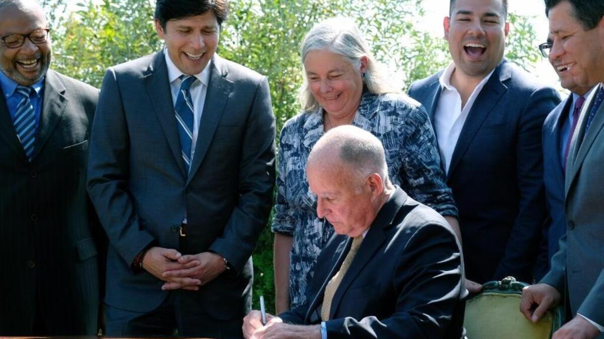 California Gov. Jerry Brown signs legislation while joined by Senate President pro tem Kevin de Leon, state Sen. Fran Pavley and others on Tuesday in Los Angeles. The law sets a new goal to reduce greenhouse gas emissions 40 percent below 1990 levels by 2030.