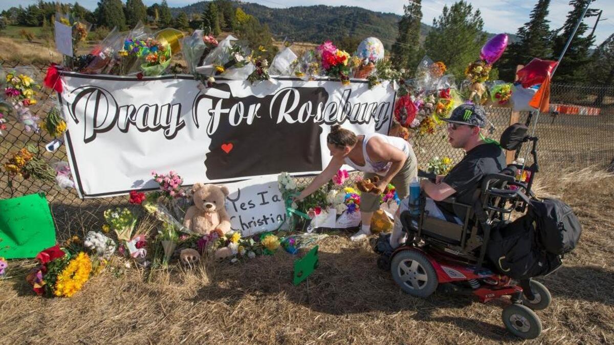 
Candida Miller, left, and Brandon Snyder leave flowers at a site of a growing memorial to victims of the mass shooting at Umpqua Community College in Roseburg, Ore.
