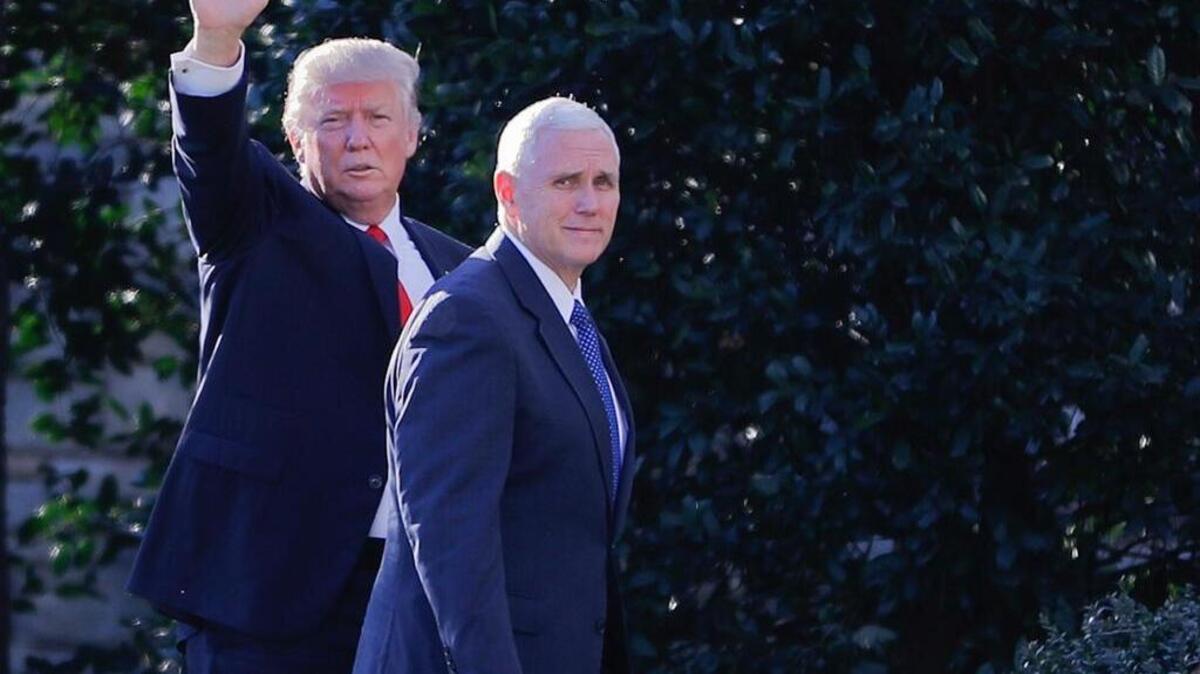 President Donald Trump, accompanied by Vice President Mike Pence, left, waves to members of the media as they walk to the Oval Office of the White House in Washington on Wednesday.