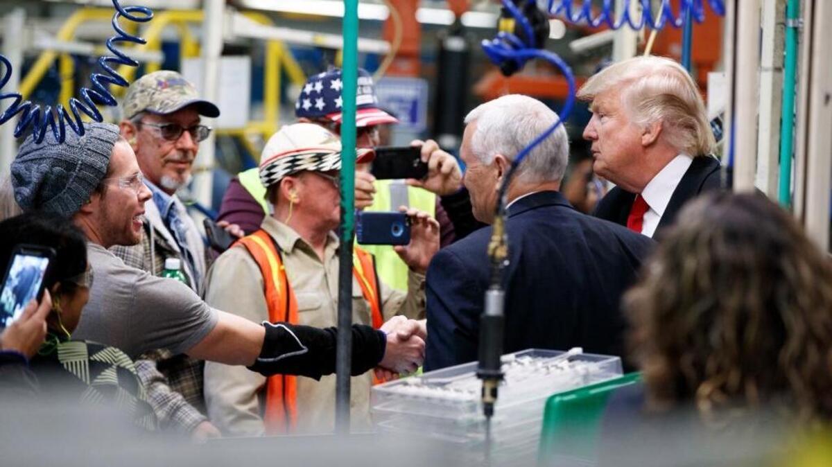 President-elect Donald Trump, far right, and Vice President-elect Mike Pence talk with factory workers Thursday during a visit to the Carrier factory in Indianapolis.