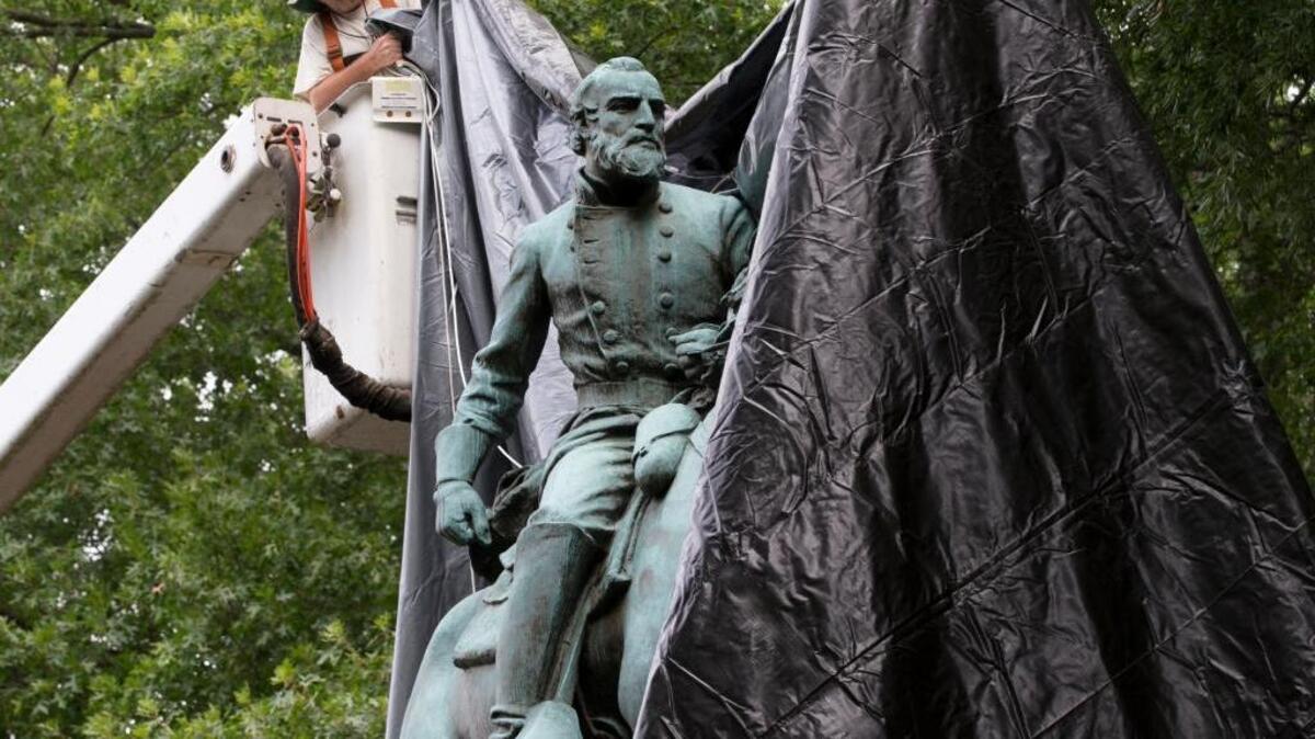 City workers drop a tarp over the statue of Confederate General Stonewall Jackson in Charlottesville, Va., on Wednesday.