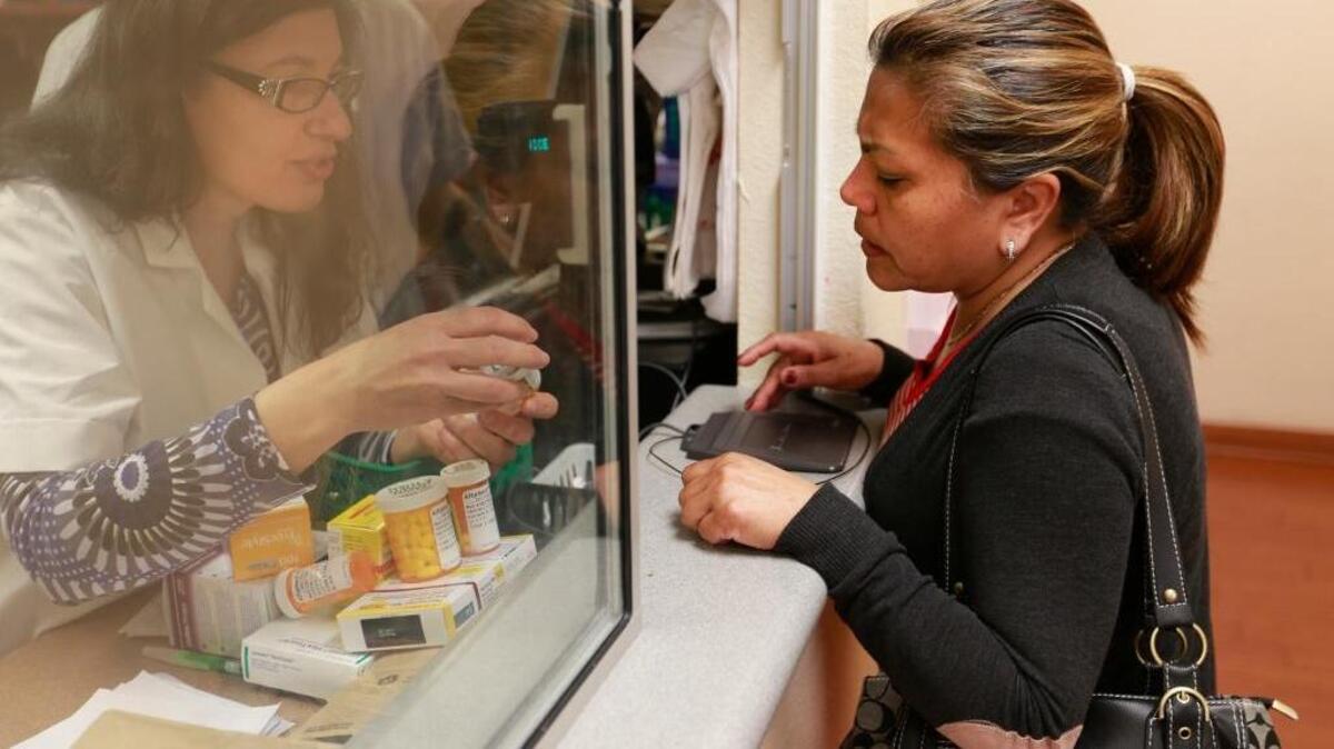 Lucia Jimenez has her prescription filled by pharmacist at AltaMed clinic in March in east Los Angeles. California’s overall health ranking is lowered by disparities based on income.
