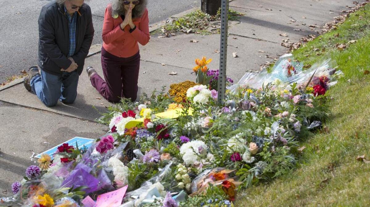 A couple kneels Sunday before a memorial in Pittsburgh for the 11 people that were killed at the shooting at the Tree of Life Synagogue.