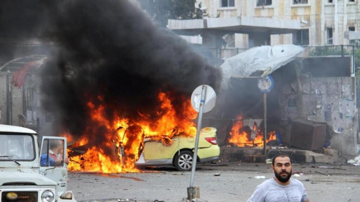 Syrians gather in front of a burning car where suicide bombers blew themselves up, in the coastal town of Tartus on Monday, May 23, 2016.