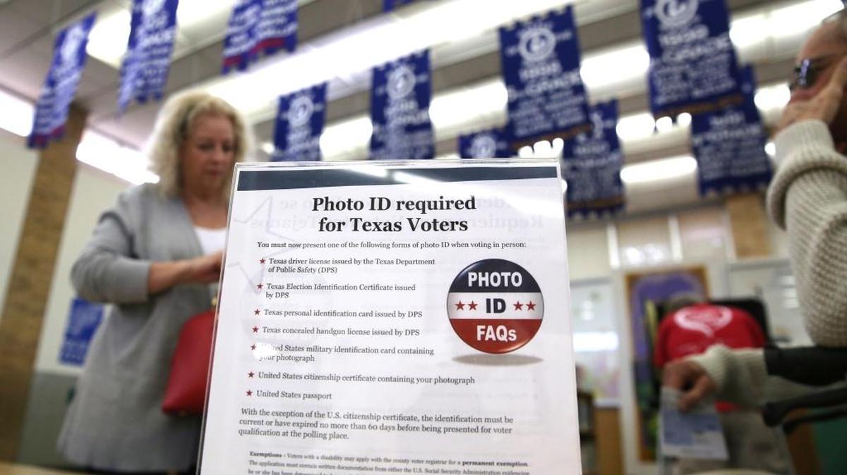 A sign tells voters of voter ID requirements before participating in the 2016 primary election at Sherrod Elementary school in Arlington, Texas.