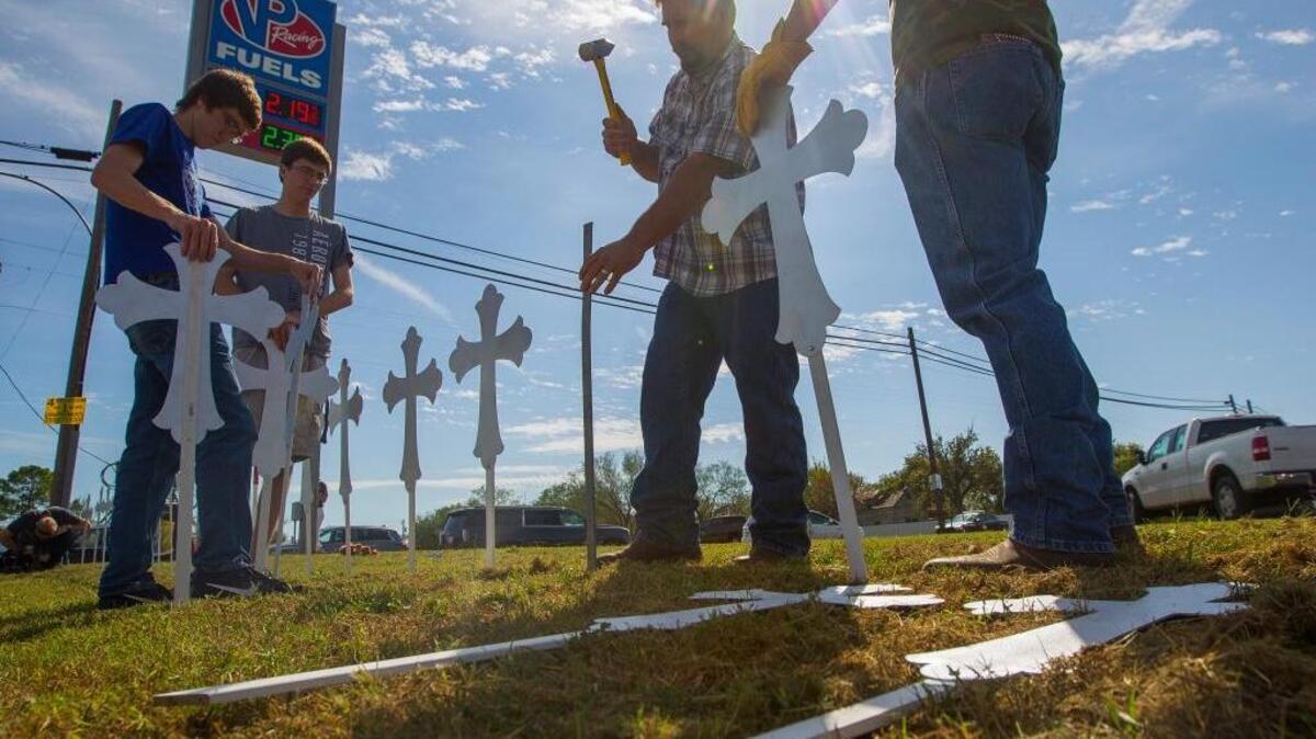 Doug John, of La Vernia, Texas, hammers in crosses Monday near the First Baptist Church of Sutherland Springs, where a mass shooting on Sunday killed at least 26 people.