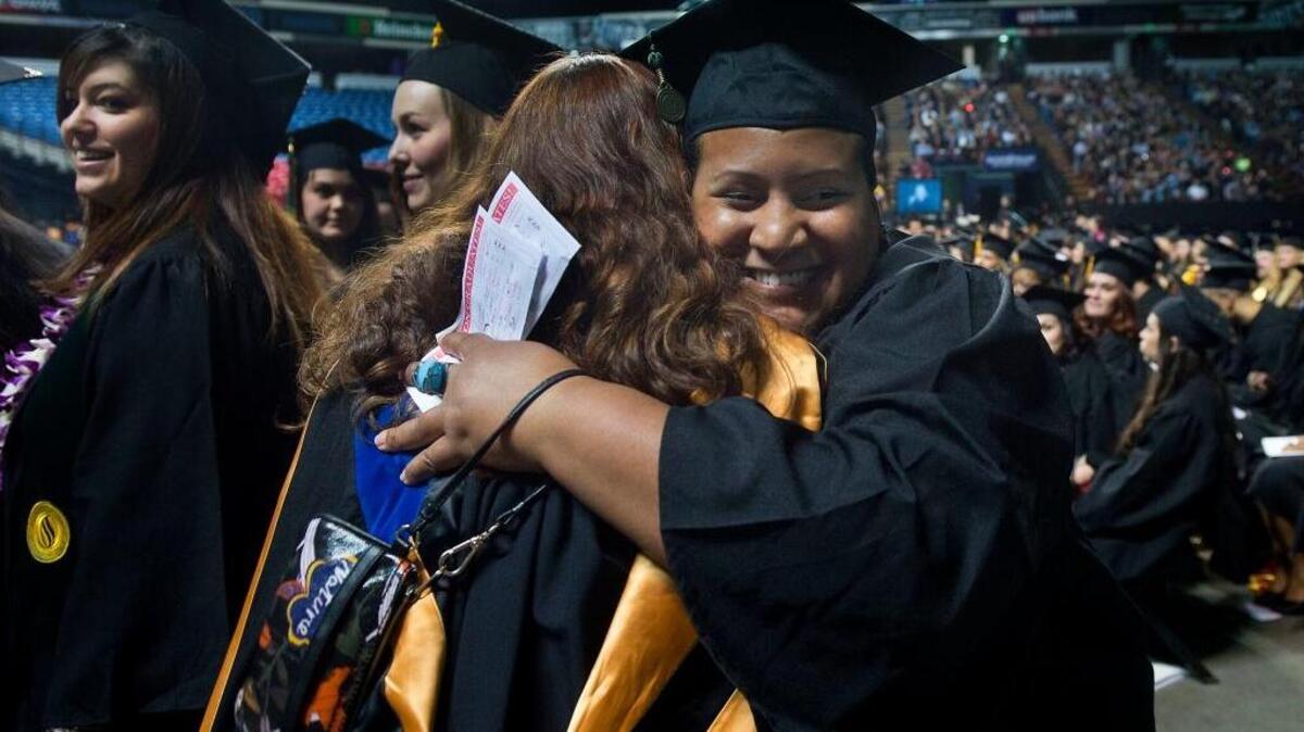 Adjunct faculty member De-Laine Cyrenne, center, hugs student Amethyst Garner during Sacramento State’s graduation ceremony in December 2013.