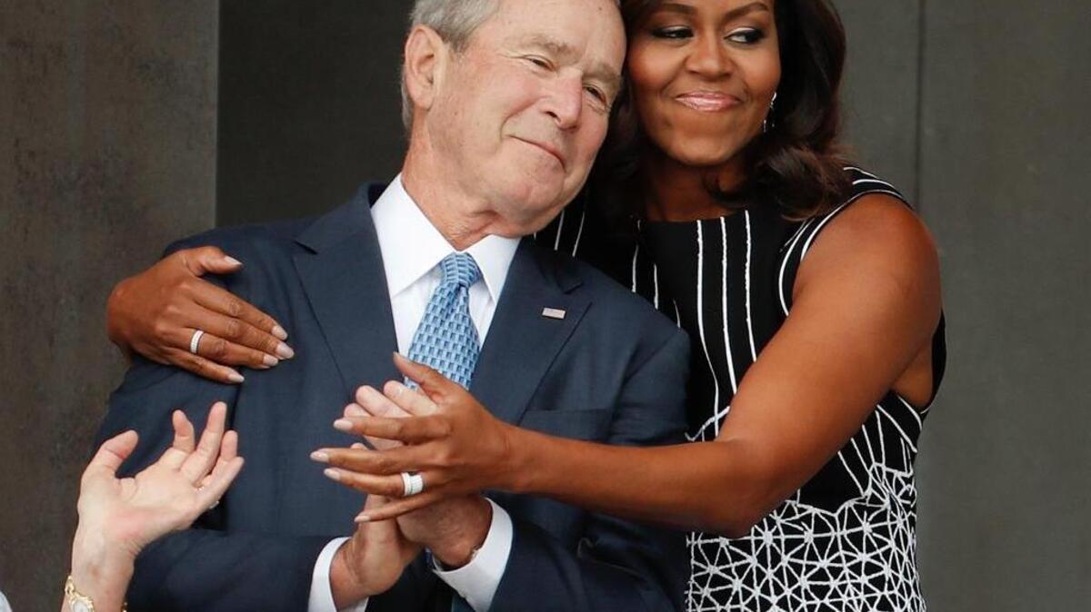 First lady Michelle Obama hugs former President George W. Bush during the dedication ceremony for the Smithsonian Museum of African American History and Culture on the National Mall in Washington on Saturday, Sept. 24, 2016.