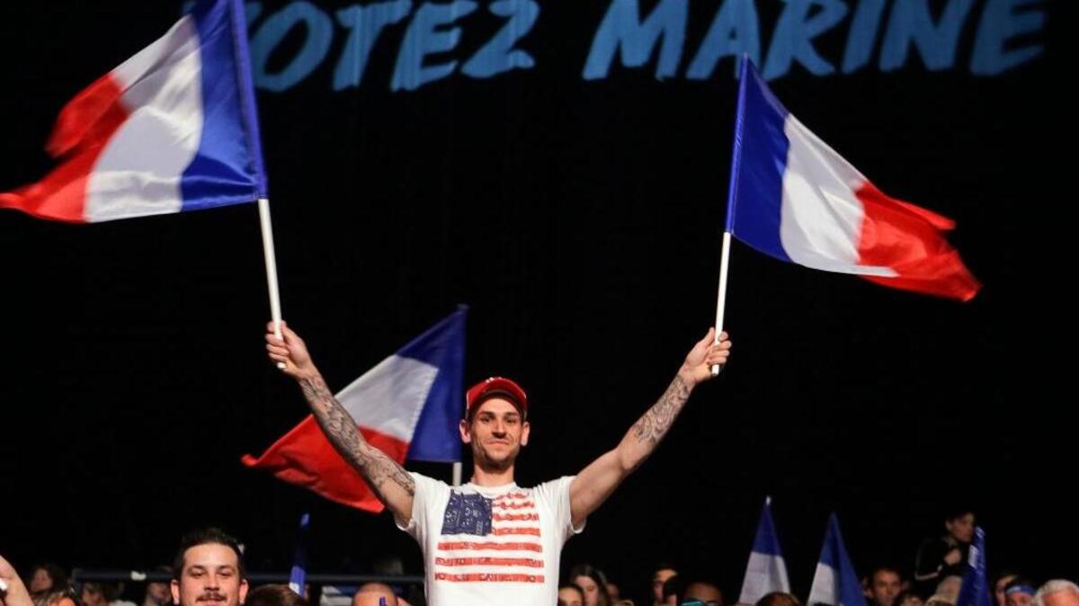 A supporter wearing an American flag T-shirt waves French flags at a campaign rally for presidential candidate Marine Le Pen in Nice on Thursday.
