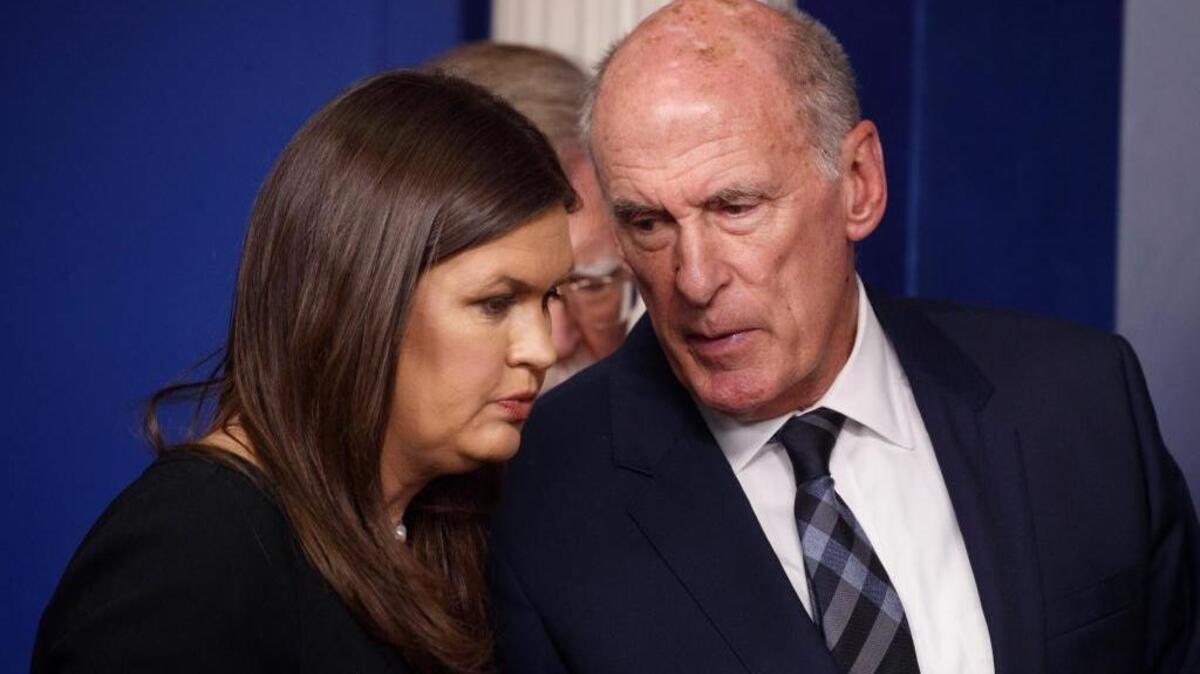 Press Secretary Sarah Huckabee Sanders speaks with Dan Coats, the director of national intelligence, during a briefing at the White House on Thursday where he said Russia was trying to influence and disrupt the November elections.