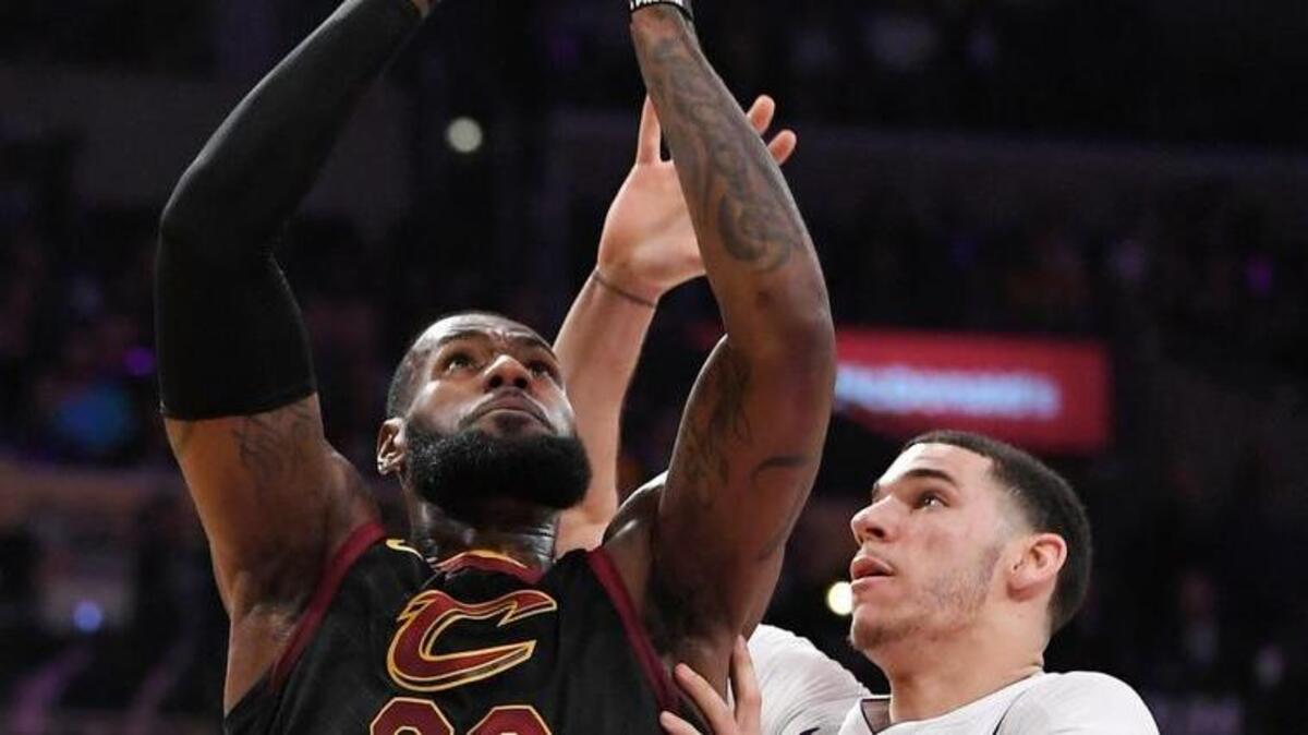 FILE - In this Sunday, March 11, 2018, file photo, Cleveland Cavaliers forward LeBron James, left, shoots as Los Angeles Lakers guard Lonzo Ball defends during the first half of an NBA basketball game, in Los Angeles. On Sunday, July 1, 2018, James announced he would be joining Ball and the Lakers to try and dethrone the Golden State Warriors and grow his own legacy. (AP Photo/Mark J. Terrill, File)