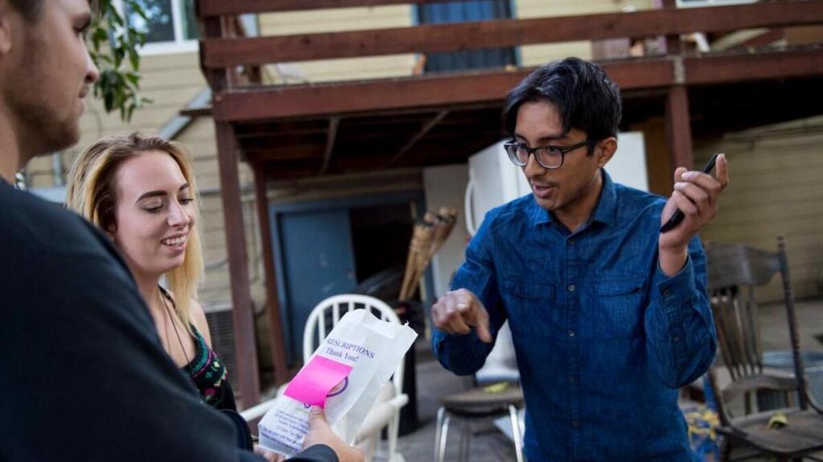 Oscar Mejia receives his medical marijuana delivery from Kody Kolstrup and Amanda Campos of GramUp on Sept. 8 in Sacramento.