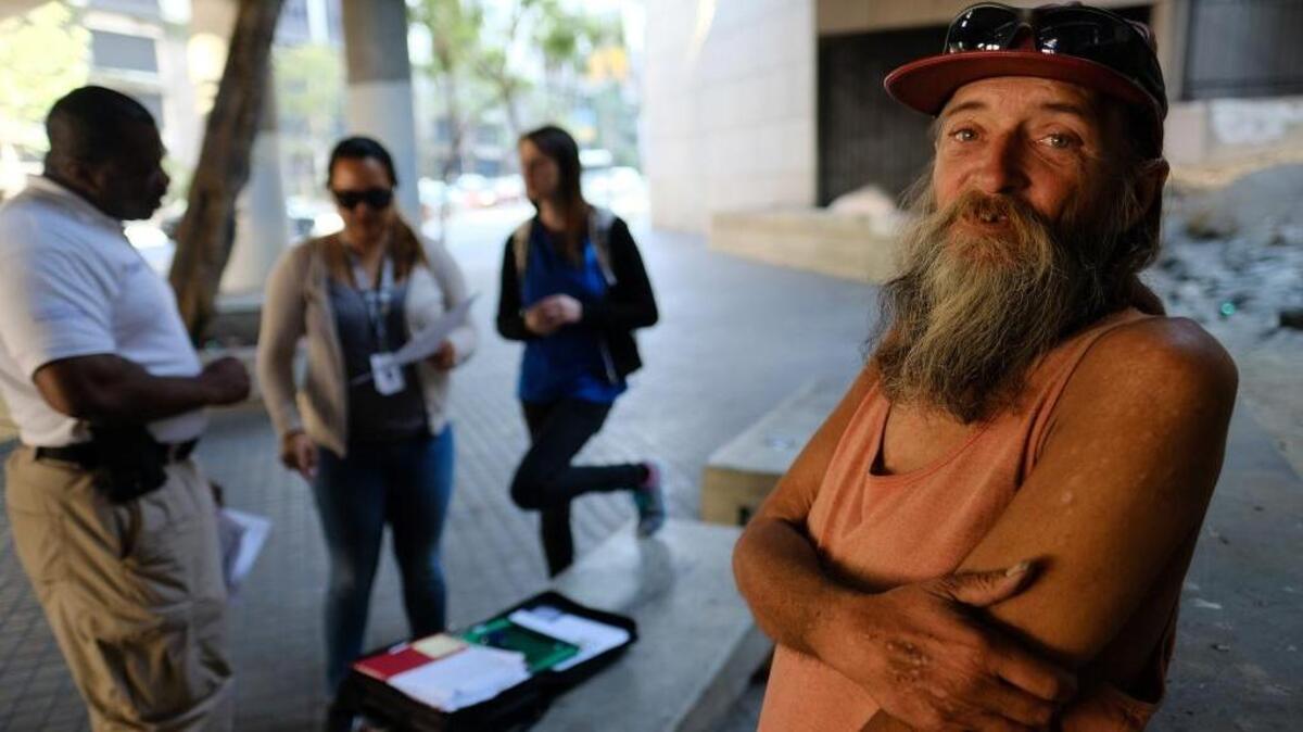 David Brophy, who is homeless, talks to outreach team members helping him get an ID card on a street near in downtown Los Angeles on June 17.
