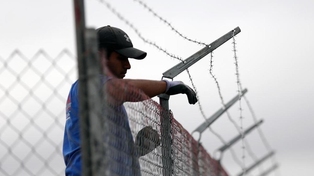 A worker installs barbed-wire on top of a fence at a U.S. Customs and Border Protection temporary holding facility near the Donna-Rio Bravo International Bridge in Texas on Dec. 7. The tent facility will primarily be used for children and families who have entered the county illegally.