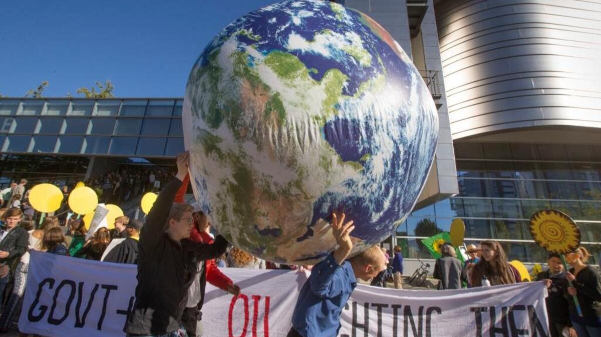 Demonstrators carry a model of the Earth past the front of the U.S. District Court in Eugene, Ore., on Tuesday, Sept. 13, 2016, to keep alive a climate change lawsuit against the U.S. government.
