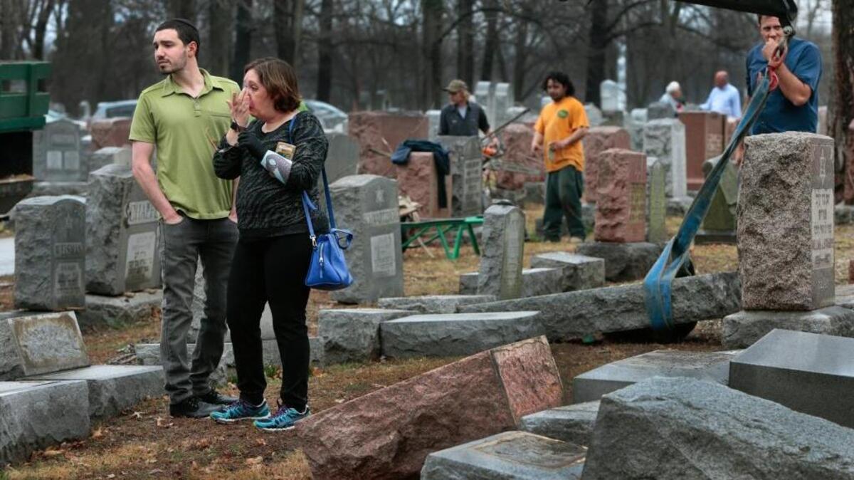 Sally Amon and her son Max Amon of Olivette, Mo., react to seeing the toppled gravestone of her grandmother Anna Ida Hutkin at Chesed Shel Emeth Cemetery in University City, a suburb of St. Louis, on Feb. 21. Vandals have damaged or tipped over as many as 200 headstones at the Jewish cemetery, leaving the region’s Jewish community shaken and anxious.