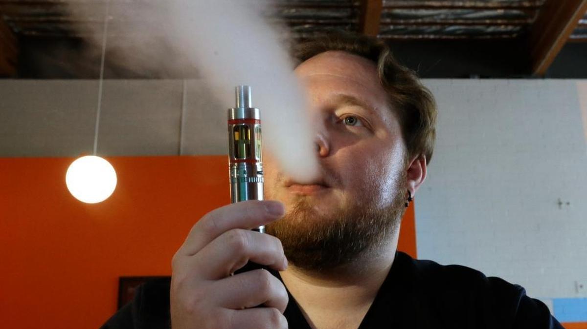 Bruce Schillin, 32, exhales vapor from an e-cigarette in Sacramento last year. A new state law treats e-cigarettes like regular cigarettes.