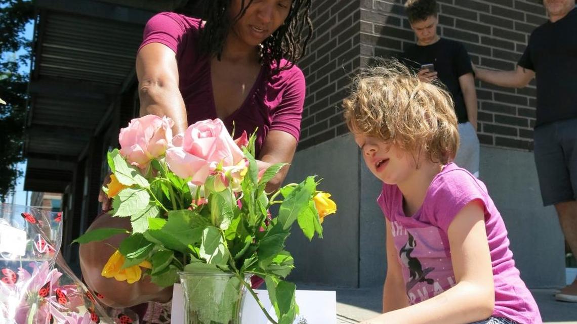 Angel Sauls, left, helps her stepdaughter, Coco Douglas arrange a sign and some painted rocks she made for a memorial in Portland on May 27 for two bystanders who were stabbed to death Friday while trying to stop a man who was yelling anti-Muslim slurs at two young women.