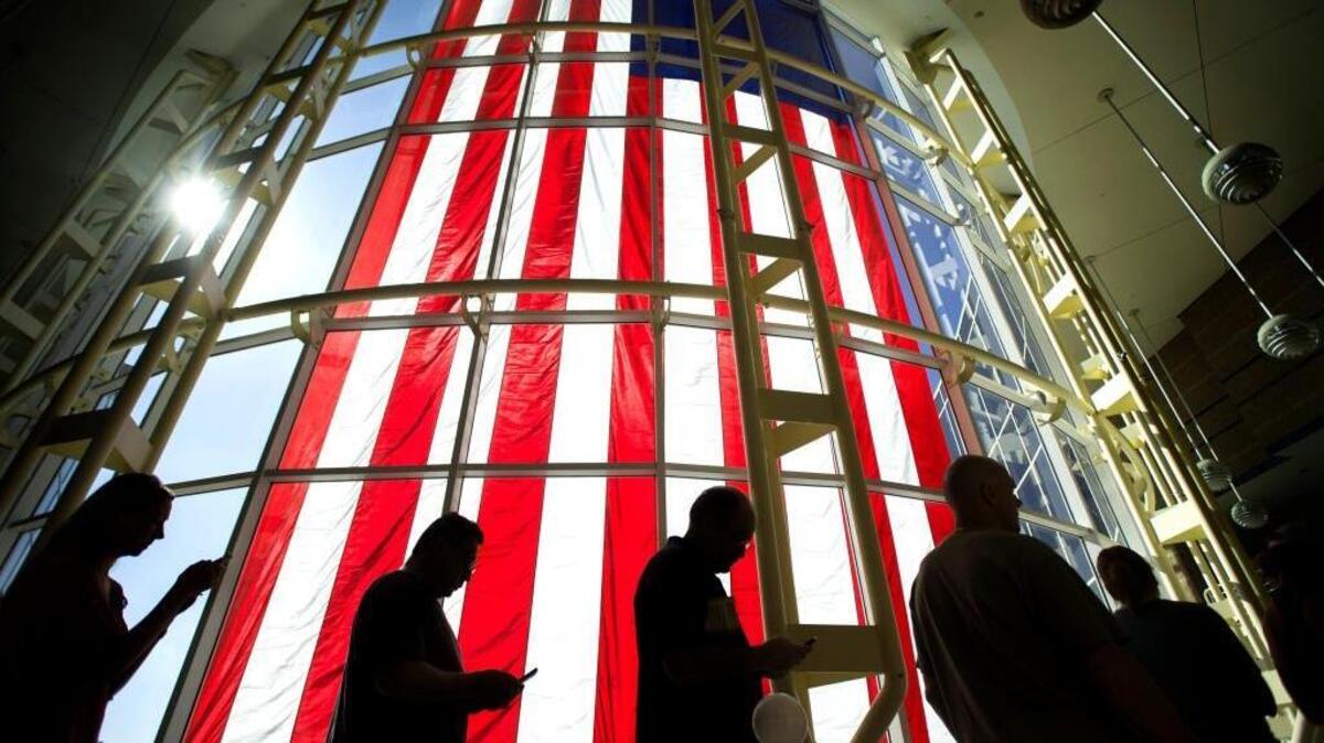 Voters wait in line under a giant American flag at City Hall in Irvine on Nov. 7. Conservative Orange County went for Hillary Clinton in the presidential election.