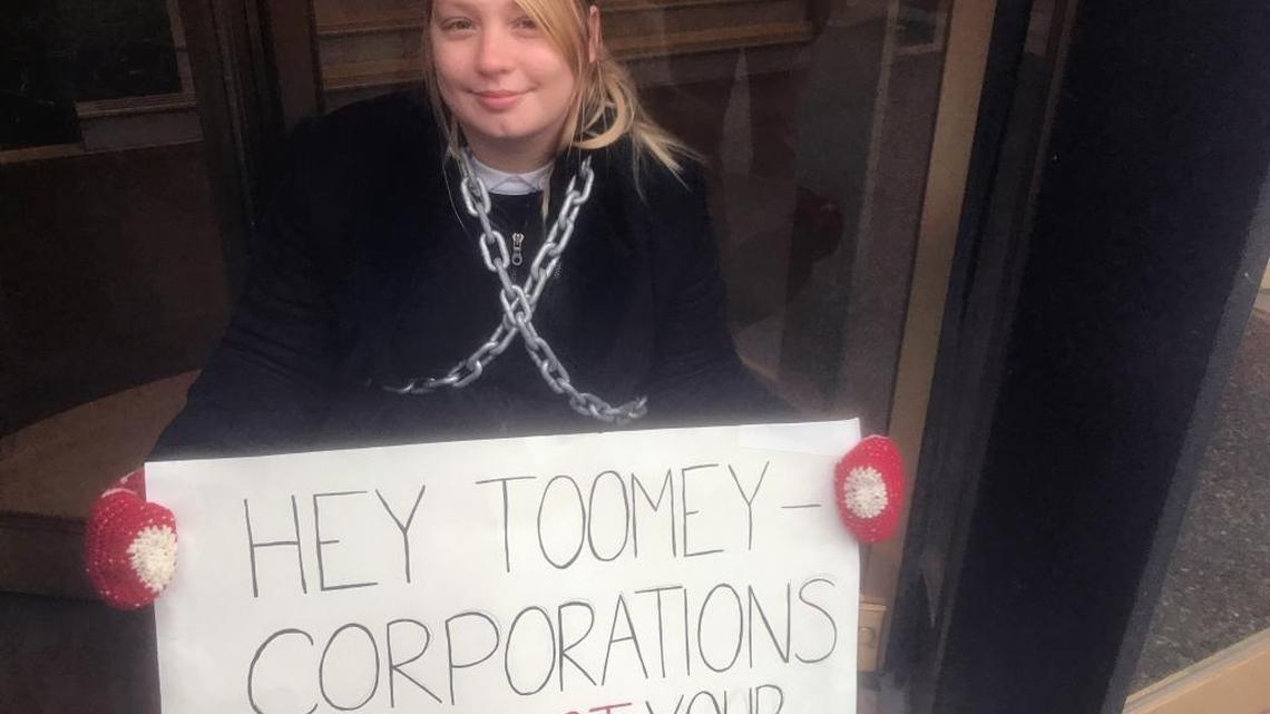 Lindsey Disler, a protester, chained herself to the entrance of U.S. Sen. Pat Toomey’s office in Pittsburgh on Monday to protest the Senate’s tax bill.