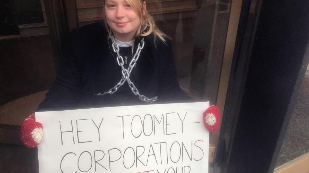 Lindsey Disler, a protester, chained herself to the entrance of U.S. Sen. Pat Toomey’s office in Pittsburgh on Monday to protest the Senate’s tax bill.