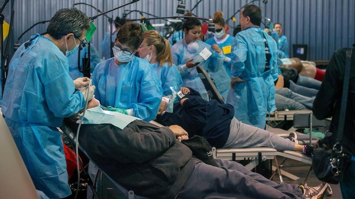 Rows of volunteers work on patients during a California Dental Association event at Cal Expo in Sacramento in March 2015. Daniel Weintraub says putting dental clinics in schools will especially help poor families.