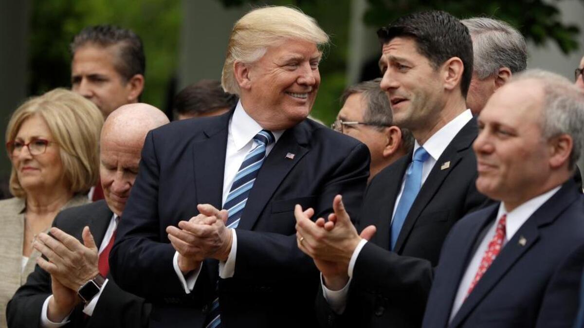President Donald Trump and House Speaker Paul Ryan of Wis. celebrate in the Rose Garden after the House pushed through a health care bill.